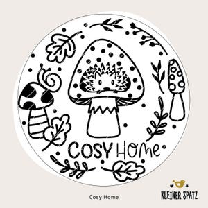 May include: Black and white illustration of a mushroom with a hedgehog inside. The mushroom has white spots and the text "Cosy Home" is written below it. There are other black and white illustrations of leaves and mushrooms around the mushroom with the hedgehog.