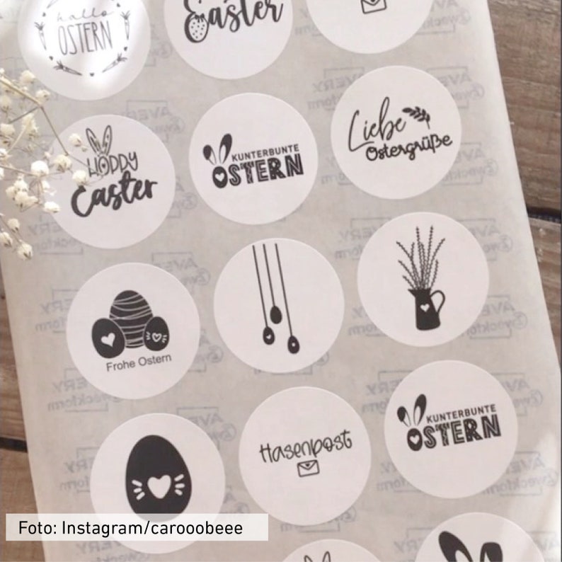 Puede incluir: Una hoja de pegatinas redondas blancas con dise&ntilde;os de Pascua negros. Los dise&ntilde;os incluyen conejos, huevos, flores y texto en alem&aacute;n e ingl&eacute;s. El texto incluye "Feliz Pascua", "Frohe Ostern", "Liebe Ostergr&uuml;&szlig;e", "Hasenpost" y "Kunterbunte Ostern".