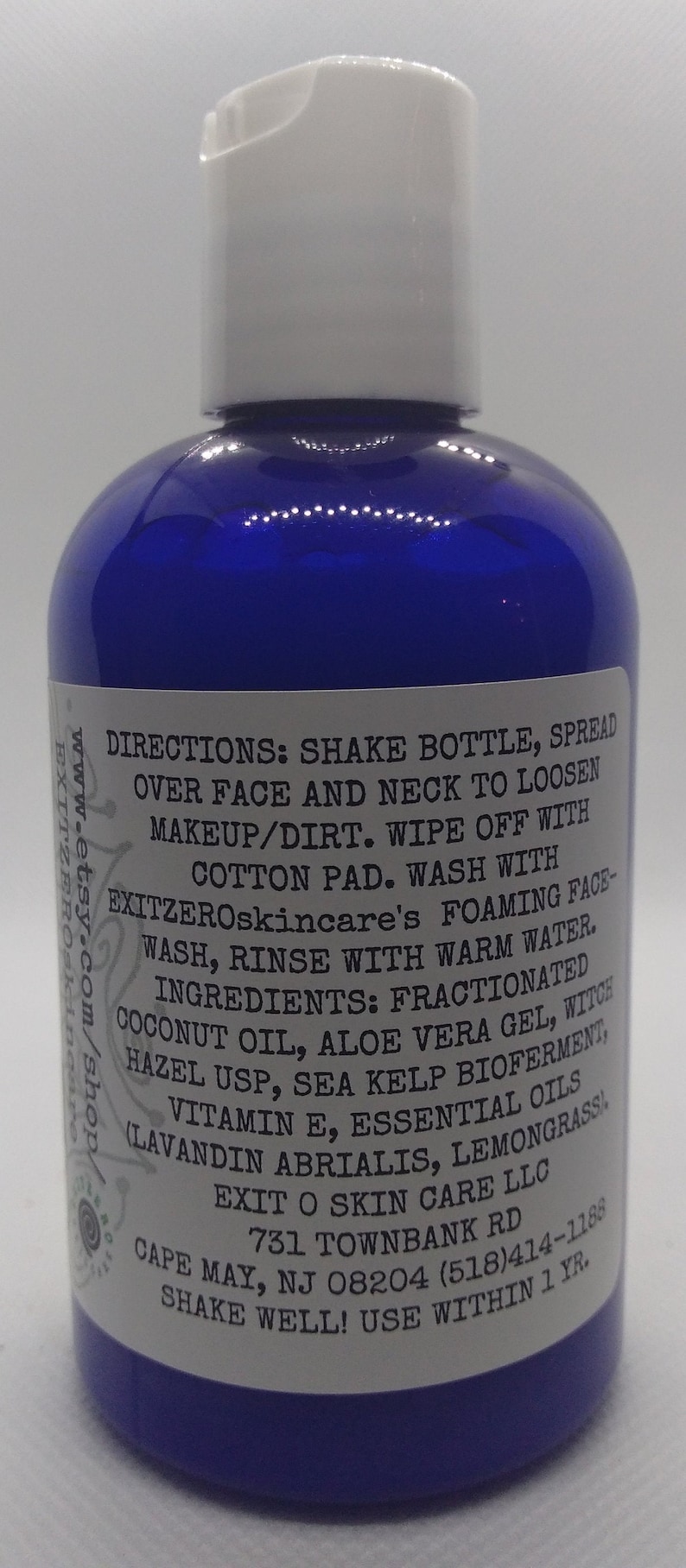 May include: A blue plastic bottle with a white cap and a white label. The label has the text "DIRECTIONS: SHAKE BOTTLE, SPREAD OVER FACE AND NECK TO LOOSEN MAKEUP/DIRT. WIPE OFF WITH COTTON PAD. WASH WITH EXITZEROskincare's FOAMING FACE-WASH, RINSE WITH WARM WATER. INGREDIENTS: FRACTIONATED COCONUT OIL, ALOE VERA GEL, WITCH HAZEL USP, SEA KELP BIOFERMENT, (LAVANDIN ABRIALIS, LEMONGRASSI VITAMIN E, ESSENTIAL OILS EXIT O SKIN CARE LLC 731 TOWNBANK RD CAPE MAY, NJ 08204 (518)414-1188 SHAKE WELL! USE WITHIN 1 YR."