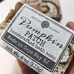 May include: A white bar of handcrafted bath soap with a black label that reads "Pumpkin Patch" and "handcrafted bath soap". The label also includes the text "Made in Cape May NJ" and "net wt. 4 oz (113g)".