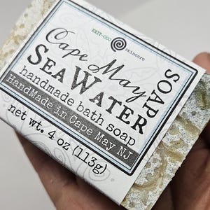 May include: A white bar of soap with a label that reads "Cape May Sea Water handmade bath soap HandMade in Cape May NJ net wt. 4 oz (113g)"