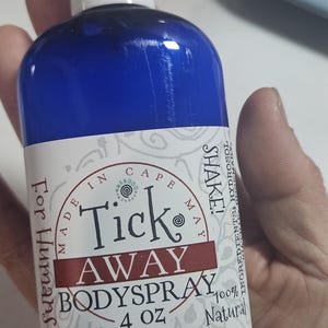 May include: A blue bottle of Tick Away Body Spray for humans. The label reads "Made in Cape May" and "100% Natural." The bottle contains 4 oz of product. The label also says "Shake!"