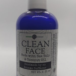 May include: A blue plastic bottle with a white label that reads "CLEAN FACE" and "Made with Sea Kelp & Coconut Oil". The label also says "Handmade by an Eczema Sufferer" and "NET WT. 4 fl oz".