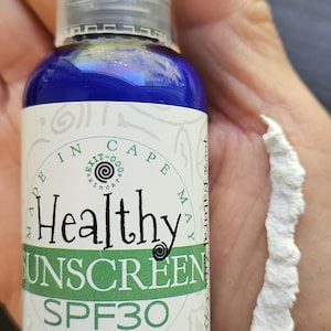 May include: A blue bottle of Healthy Sunscreen SPF 30, made in Cape May, with a white label and a swirl design. The bottle contains 2 oz of sunscreen.