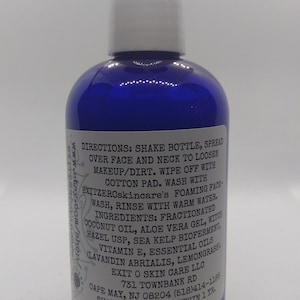 May include: Blue plastic bottle with a white cap and a white label with black text. The label includes directions for using the product, a list of ingredients, and contact information for the company. The text on the label reads: "DIRECTIONS: SHAKE BOTTLE, SPREAD OVER FACE AND NECK TO LOOSEN MAKEUP/DIRT. WIPE OFF WITH COTTON PAD. WASH WITH EXITZEROskincare's FOAMING FACE-WASH, RINSE WITH WARM WATER. INGREDIENTS: FRACTIONATED COCONUT OIL, ALOE VERA GEL, WITCH HAZEL USP, SEA KELP BIOFERMENT, VITAMIN E, ESSENTIAL OILS (LAVANDIN ABRIALIS, LEMONGRASS) EXIT O SKIN CARE LLC 731 TOWNBANK RD CAPE MAY, NJ 08204 (518)414-1186 SHAKE WELL! USE WITHIN 1 YR."