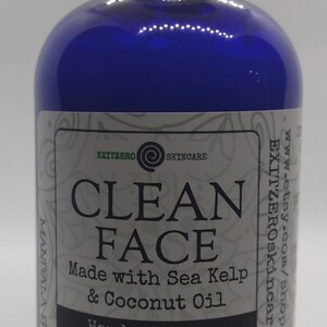 May include: A blue bottle with a white cap and a white label that reads "CLEAN FACE Made with Sea Kelp & Coconut Oil Handmade by an Eczema Sufferer NET WT. 4 fl oz"