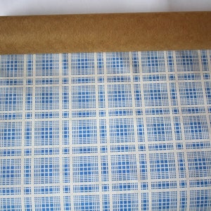 K&ouml;nnte beinhalten: Eine Rolle blaues und wei&szlig;es kariertes Geschenkpapier mit einem braunen Pappkern.