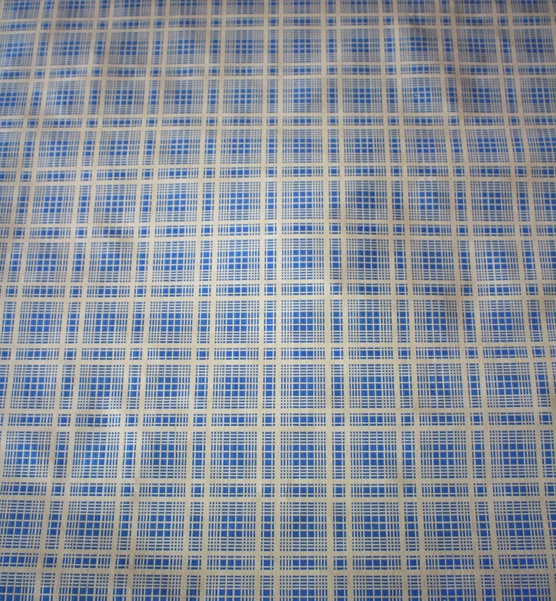K&ouml;nnte beinhalten: Ein beigefarbener Stoff mit einem blau-wei&szlig;en Karomuster. Der Stoff hat einen dezenten Glanz und eine leicht knitterige Textur.