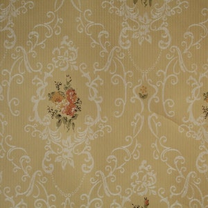Pode incluir: Um papel de parede vintage com fundo amarelo e um padrão floral branco. O padrão apresenta delicados redemoinhos e pequenos buquês de flores rosa e laranja.