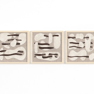 May include: Three framed abstract art prints with a beige background and brown abstract shapes. The frames are made of natural wood.