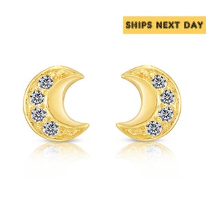 May include: A pair of gold crescent moon earrings with small clear cubic zirconia stones set in the crescent.