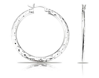 May include: A pair of silver hoop earrings with a textured finish. The earrings are circular and have a simple design.