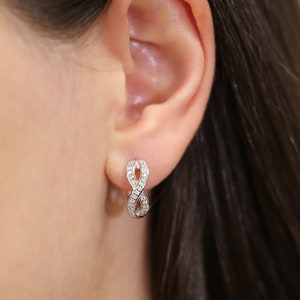 May include: Silver infinity earrings with small clear cubic zirconia stones.