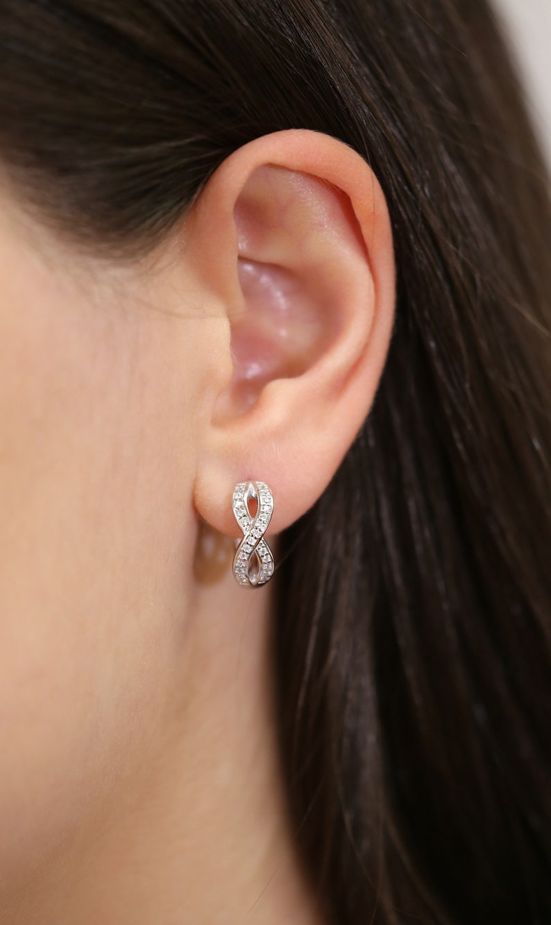 May include: Silver infinity earrings with small clear cubic zirconia stones.