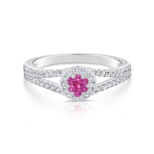 May include: A silver ring with a pink gemstone surrounded by smaller white gemstones. The ring has a delicate split band design.