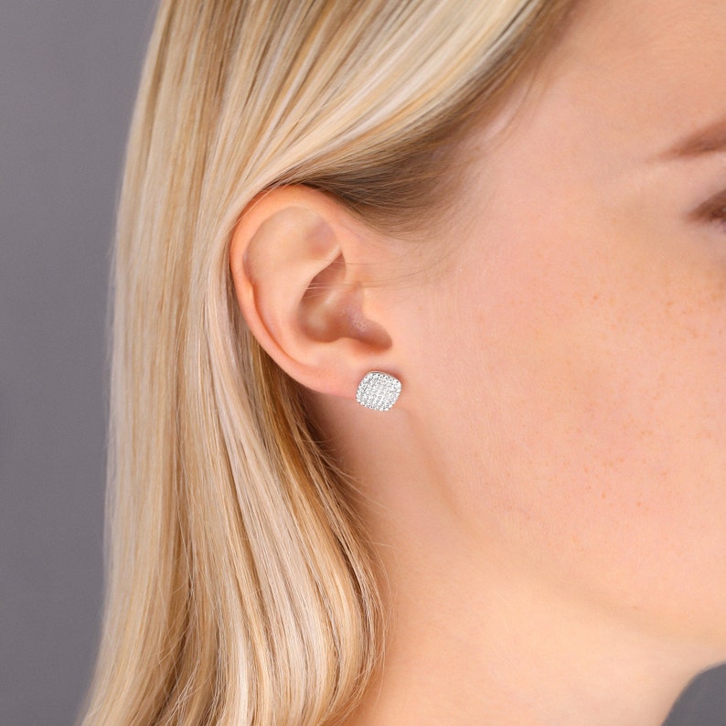 May include: A pair of silver stud earrings with a square-shaped design featuring a cluster of small, clear diamonds.
