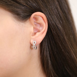 May include: Silver infinity hoop earrings with small clear cubic zirconia stones.