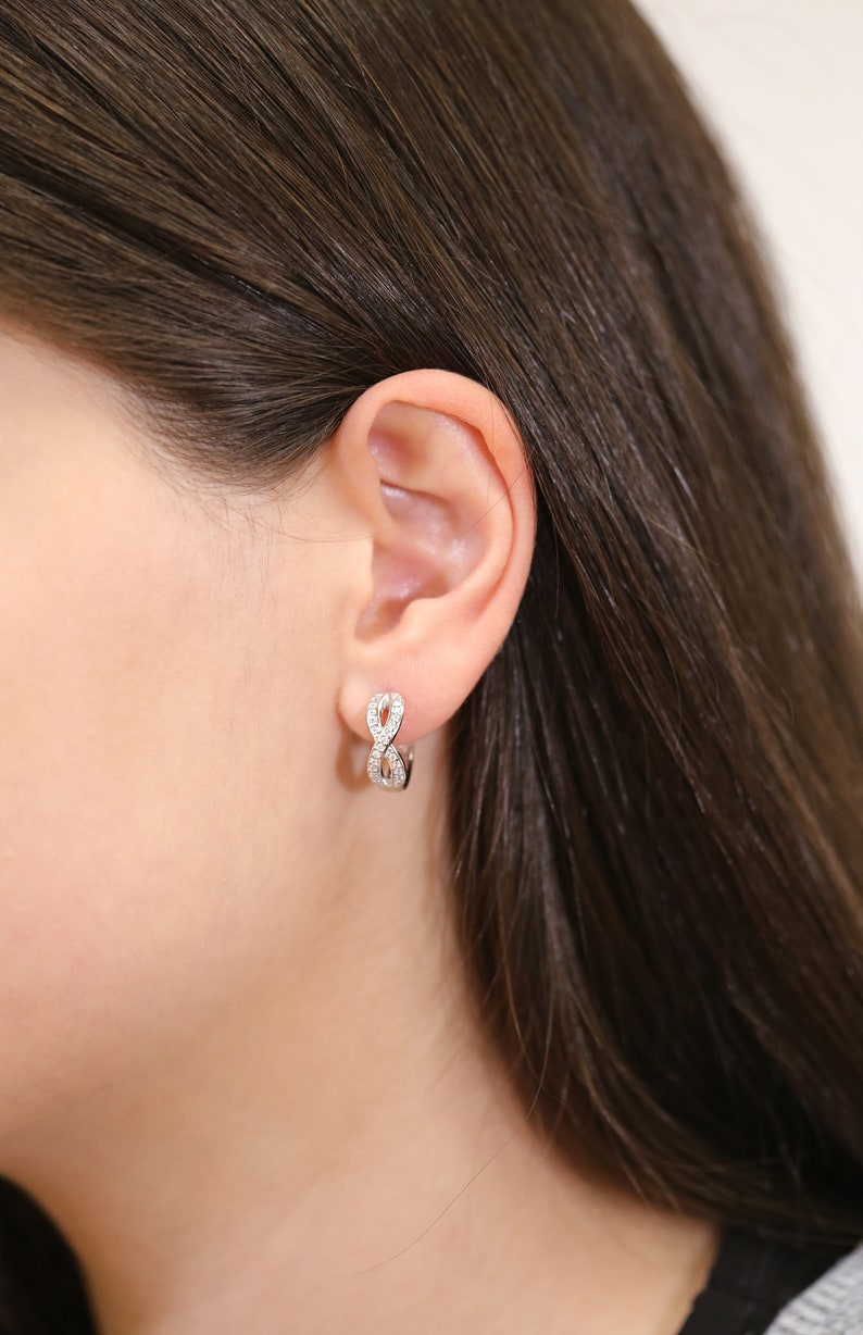 May include: Silver infinity hoop earrings with small clear cubic zirconia stones.