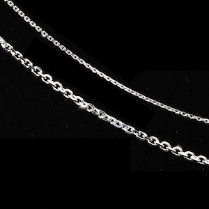May include: Two silver chains, one thicker than the other, are laid out on a black background. The chains are made of interlocking oval links.