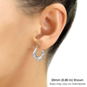 May include: A silver-toned hoop earring with a diamond-shaped profile and a textured, faceted surface. The earring measures 0.80 inches in size as indicated by the text 20mm (0.80 in) Shown. The design features a hinged closure mechanism.