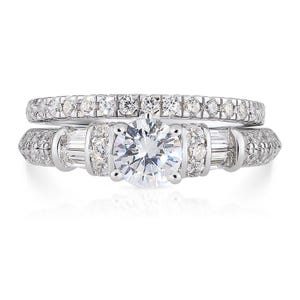 May include: A silver wedding ring set with a large round center stone and smaller stones around the band. The band is accented with baguette-shaped stones.