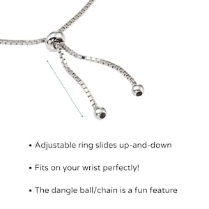 May include: A silver chain bracelet with an adjustable ring and a dangling ball charm. The ring slides up and down the chain to adjust the bracelet's size.