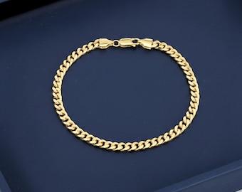 May include: A gold-colored metal chain bracelet featuring a classic curb link design. The bracelet is circular in shape and includes a secure lobster claw clasp mechanism at the top, connecting the two ends of the polished, interlocking metal links.