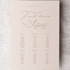 May include: A seating chart for a wedding reception with the text "Finde deinen Sitzplatz" (Find your seat) in cursive script. The chart lists tables numbered 1 through 6 with the names of guests assigned to each table.