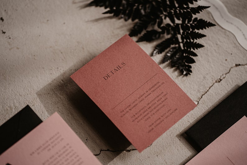 May include: A red card with the word "DETAILS" printed in black. The card has text about a wedding ceremony and reception, including the date, time, and location.