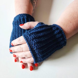 May include: A pair of blue crocheted fingerless gloves with red nail polish on the fingers.