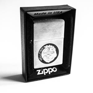 Peut inclure: Un briquet Zippo argenté dans une boîte noire. Le briquet présente un graphisme circulaire avec le mot "HELLFISH" et un personnage de dessin animé. Le logo Zippo est imprimé en dessous. La boîte indique "Made in USA".