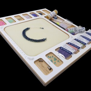Acclaim Crafts Seed Beaders Dream Board in use with colorful seed beads, beading supplies, and a finished blue woven bracelet.
