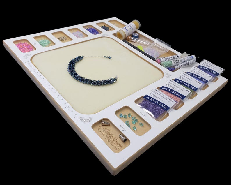 Acclaim Crafts Seed Beaders Dream Board in use with colorful seed beads, beading supplies, and a finished blue woven bracelet.