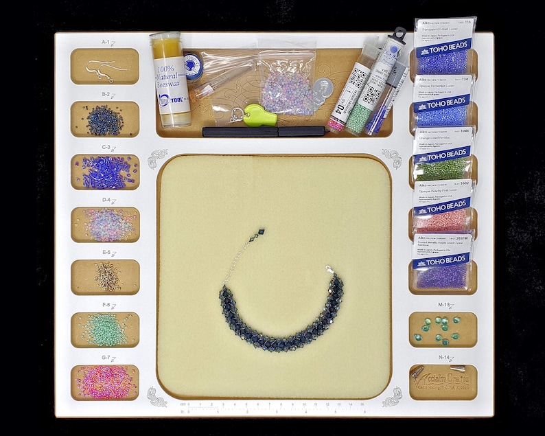 Organized workspace of the Acclaim Crafts Seed Beaders Dream Board holding beading wax, needles, seed beads, and a bracelet.