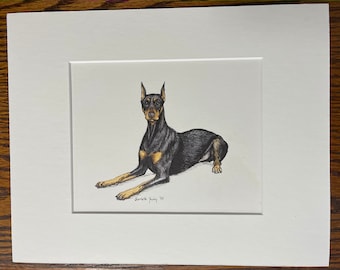Könnte beinhalten: Ein schwarz-brauner Dobermann liegt mit dem Kopf nach links gedreht. Der Hund ist in Schwarzweiß auf weißem Papier gezeichnet. Die Unterschrift des Künstlers befindet sich in der rechten unteren Ecke des Bildes.