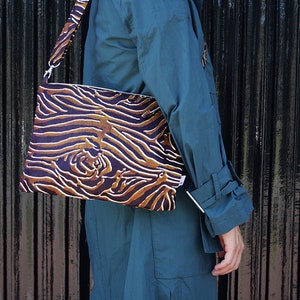 Op de afbeelding: Een bruine en zwarte zebraprint crossbody tas met een lange band.