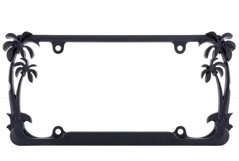 May include: Black license plate frame with palm tree accents. The frame is rectangular with rounded corners and features palm tree silhouettes at each corner. Includes mounting holes for easy installation.