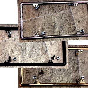 May include: Three license plate frames, one chrome, one black, and one gold. Each frame has four screw holes and two tabs on the top.