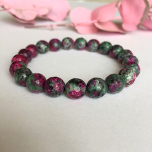 May include: A green and pink gemstone bracelet with faceted beads. The bracelet is made of natural stones and is a beautiful and unique piece of jewelry.