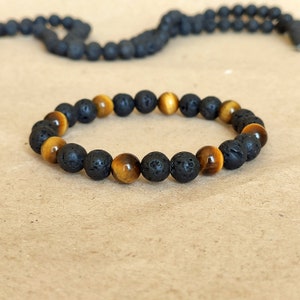 May include: A black lava rock and tiger's eye beaded bracelet. The bracelet is made of alternating black lava rock and tiger's eye beads.