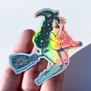 Könnte beinhalten: Holografischer Aufkleber mit einer Hexe auf einem Besen, mit einem Regenbogenverlauf. Die Hexe hat langes, sternenbesetztes Haar und einen spitzen Hut. Der Aufkleber enthält den Text "@guidedhandstudio".