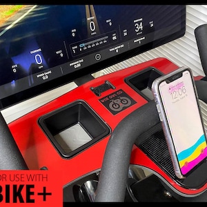 May include: A red and black stationary bike with a phone holder and a screen displaying workout data. The screen shows the text "FOR USE WITH BIKE+".