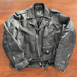 May include: Black leather biker jacket with a zip fastening, two front pockets, and a belt. The jacket has a label that reads "UNIK INTERNATIONAL INC."