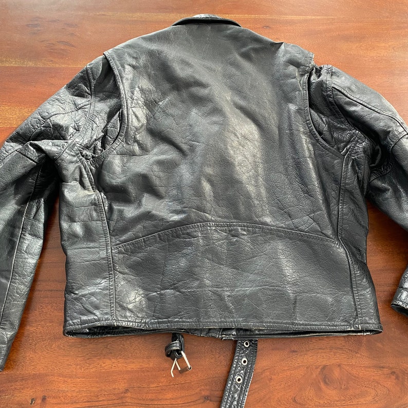 May include: Black leather motorcycle jacket with a zip fastening and a belt at the waist.