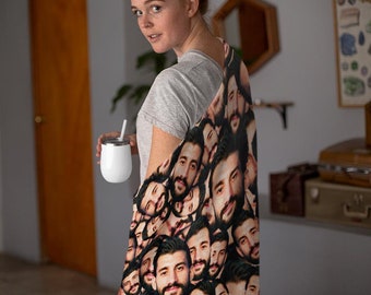 May include: A soft throw blanket featuring a repeating pattern of a man's face with a dark beard and mustache. The blanket is draped over a shoulder, showcasing the continuous print of the same individual's portrait across the fabric surface.