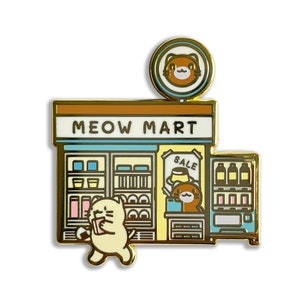 May include: A gold-colored enamel pin featuring a cartoon illustration of a convenience store called "MEOW MART". The store has a cat-shaped sign above the entrance, a window with shelves of goods, and a vending machine. A cat character is walking out of the store with a drink.