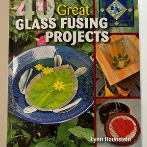 May include: A book cover titled "40 Great Glass Fusing Projects" featuring images of fused glass art. The cover includes a turtle design, a stained glass panel, and other projects. The author's name is Lynn Haunstein.