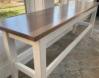 May include: A white wooden bench with a brown wood top. The bench has a simple design with straight legs and a single support beam.