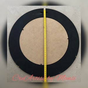May include: A black round picture frame with a wood backing. The frame is 39 inches in diameter.
