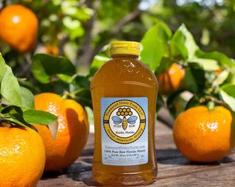 May include: A clear plastic bottle filled with amber-colored honey, featuring a yellow cap and a label that reads Townsend Honey Farm LLC, Sweet American Honey, Starks, Florida, 100% Pure Raw Florida Honey, Net Wt. 32 oz. (2 lb.) 907 g.